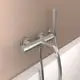 Edelstahl-Wannenarmatur von Ideal Standard mit Handbrause und flexiblem Schlauch. Montage an der Wand mit zwei Befestigungselementen, hinter einem hellen Wandpaneel.